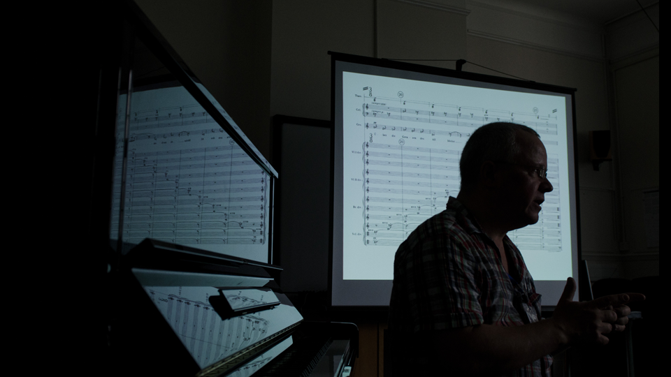 A dark photo of a composer at a piano